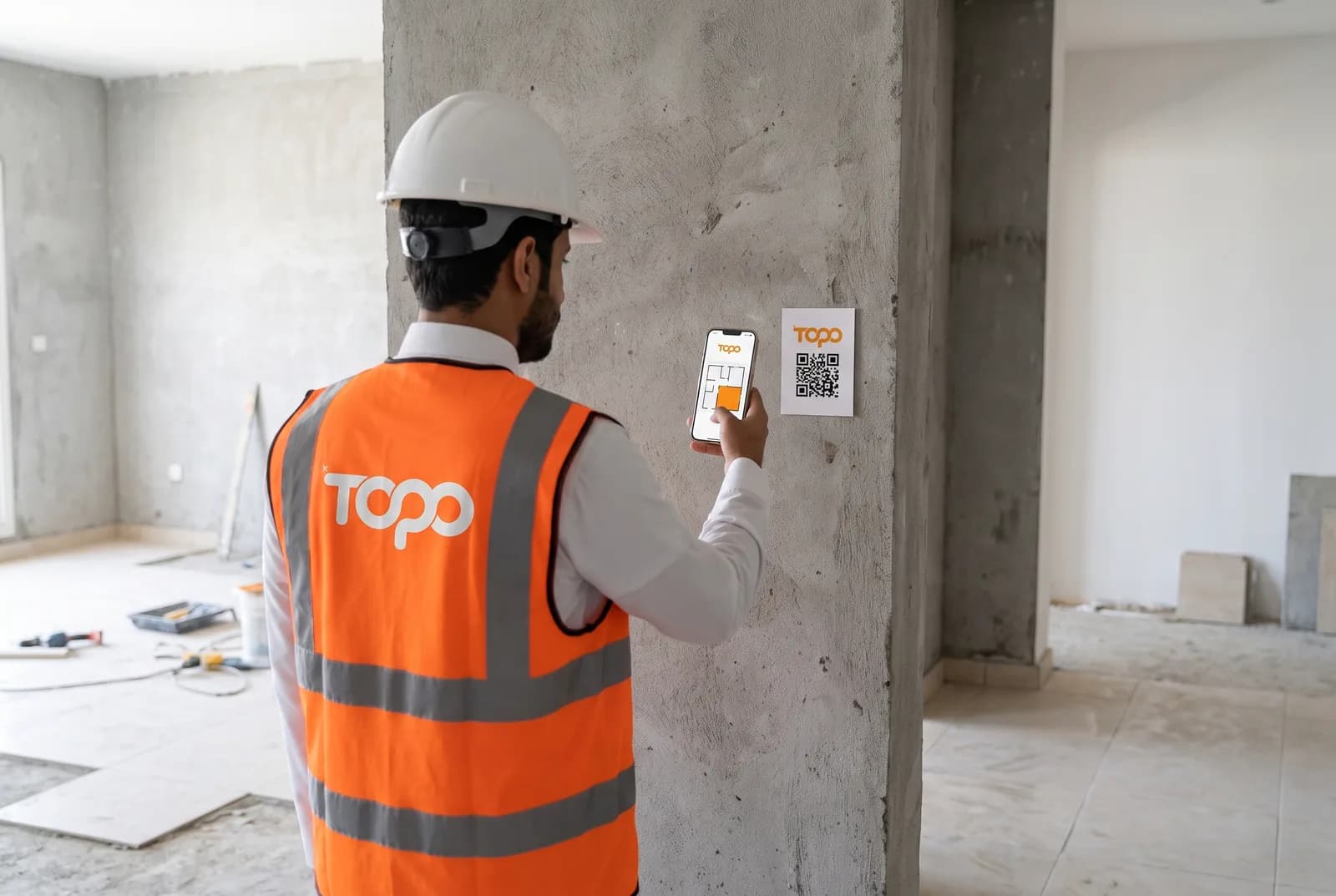 مهندس موقع يمسح رمز QR على جدار خرساني بجواله